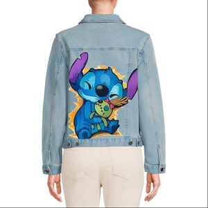 May include: A light blue denim jacket with a cartoon image of Stitch from Lilo & Stitch holding a doll. The image is on the back of the jacket.