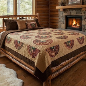 May include: A rustic bedroom scene featuring a wooden bed frame and a patterned quilt. The quilt showcases a beige background with repeating fan-shaped designs in shades of red, green, and brown. Brown pillows and a dark brown bed skirt complement the quilt's colors.