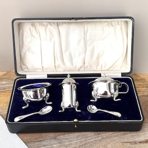 Juego de aceiteras, vinagreras y mostaza de plata antigua en caja, con forros de vidrio azul.