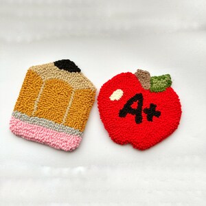 May include: Two felt crafts, a yellow pencil and a red apple with a white A+ on it.
