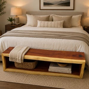 May include: A rectangular wooden bench with a live edge top and a hollow base featuring an open storage shelf. The bench is topped with a folded cream-colored knit throw blanket, while the lower shelf holds a woven basket and two stacked books.