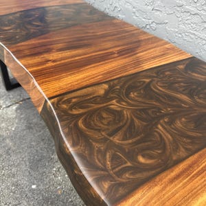 May include: A wooden bench with a live edge top and a dark brown epoxy resin inlay. The bench has a natural wood finish and a black metal base.