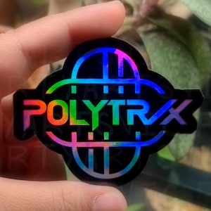 May include: A black sticker with the word "POLYTRX" in rainbow gradient lettering. The sticker has a unique shape with a colorful, geometric design around the text. The sticker is held in a hand.