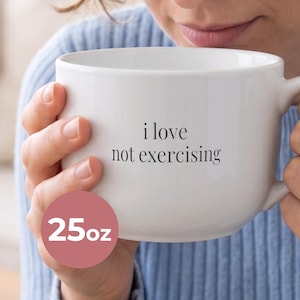May include: A large white ceramic mug with a 25oz capacity, featuring the black text 'i love not exercising' printed on the front. The mug has a smooth, rounded body and a sturdy handle, designed for holding a substantial volume of hot beverage.