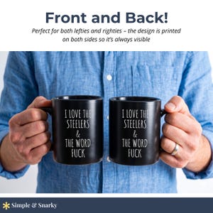 May include: Two black ceramic mugs featuring white text that reads I LOVE THE STEELERS & THE WORD FUCK. The mugs have a smooth matte finish and a standard handle design. The text is printed clearly on the front of each mug in a simple sans-serif font.