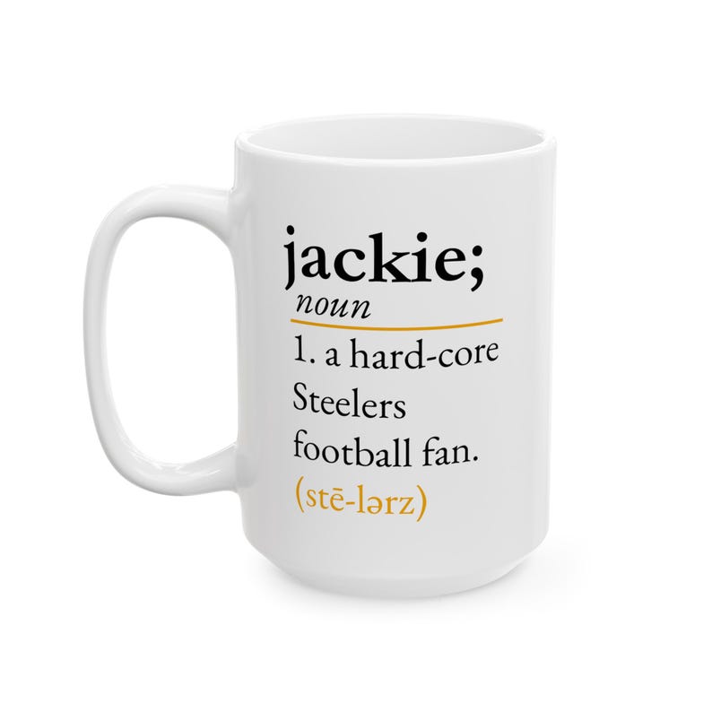 May include: A white ceramic mug featuring black text that reads: jackie; noun 1. a hard-core Steelers football fan. The text includes a gold horizontal line and the phonetic pronunciation (stē-lərz) in gold text at the bottom of the definition.