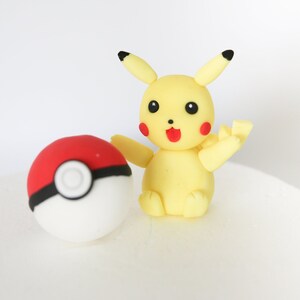 Puede incluir: Una figura de Pikachu amarilla con mejillas rojas y nariz negra, sosteniendo una Pok&eacute; Ball roja y blanca con una banda negra.