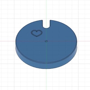 May include: A blue circular object with a heart-shaped cutout. The object has a small hole in the center.