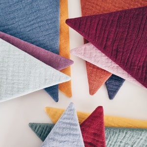 May include: A collection of triangular fabric pieces in various colors, including blue, purple, red, orange, and green. The fabric has a textured, quilted appearance.