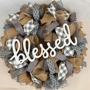 May include: A gray, white, and brown burlap wreath with a white wooden sign that says "blessed".