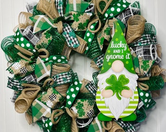 Op de afbeelding: Een groene, witte en zwarte St. Patricks Day krans met een gnome-uitsparing waarop "lucky and I gnome it" staat. De krans is gemaakt van jute, gaas en lint.