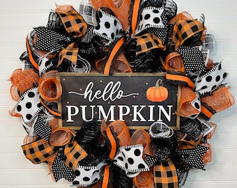 May include: A black and orange Halloween wreath with a sign that says "hello pumpkin". The wreath is made of mesh, ribbon, and burlap.