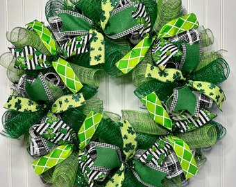 Op de afbeelding: Een groene, witte en zwarte St. Patricks Day krans met klavertjevier en ruitjes lint strikken.