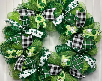 Op de afbeelding: Een groene, witte en zwarte St. Patricks Day krans met klavertjevier en geruite strikken.