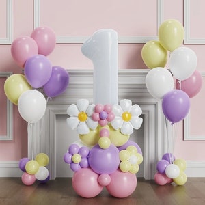 May include: A white number one balloon with pink, yellow and white flower decorations. The balloon is surrounded by a variety of pastel coloured balloons, including purple, pink, yellow and white.