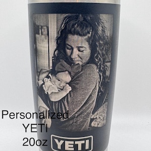 Puede incluir: Vaso YETI negro con una imagen personalizada en escala de grises de una madre y un niño. El vaso tiene un borde y una tapa plateados. El texto en el vaso dice "Personalizado YETI 20oz 30oz Y más."
