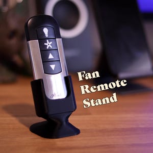 May include: A black fan remote control stand with a silver remote control inside. The remote has buttons for light, fan speed, and direction. The stand has the word "Home" printed on it.  Fan Remote Stand