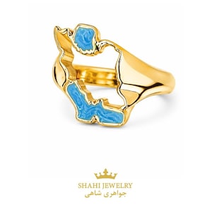 May include: A gold-colored ring with a unique design, featuring a cutout shape filled with light blue enamel. The ring has a smooth, polished finish and the text "SHAHI JEWELRY" is visible below the ring.