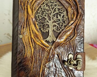 May include: A brown leather journal with a tree of life design embossed on the front cover. The journal has a metal clasp and is decorated with stitching and rivets.