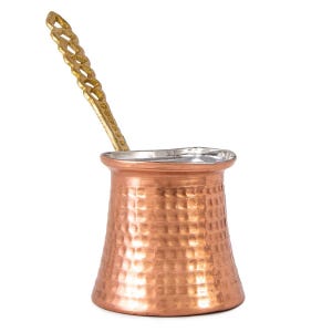 May include: A copper-colored Turkish coffee pot with a hammered texture and a silver-colored rim. A gold-colored handle extends from the pot. The pot is designed for brewing coffee and has a traditional shape.