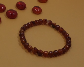 May include: A brown beaded bracelet with a string closure. The bracelet is made of small, round beads.