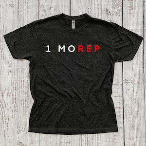 May include: A black t-shirt with the text "1 MORE REP" in white and red letters.