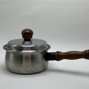 May include: A silver saucepan with a wooden handle and a lid. The lid has a wooden knob.