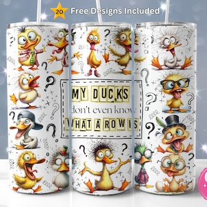 May include: A white cylindrical tumbler featuring a repeating pattern of cartoon ducks with various expressions and accessories. The text reads MY DUCKS don't even know WHAT A ROW IS. The design includes black question marks and scribbles on a white background.