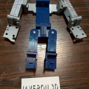 Könnte beinhalten: Ein zerlegtes Roboter-Spielzeug in Blau- und Grautönen, mit beweglichen Gliedmaßen und einem rechteckigen Torso. Der Roboter besteht aus Kunststoff und hat ein detailliertes Design. Eine Visitenkarte mit dem Text "JAVERON 3D CUSTOM PRINTING AND DESIGN" befindet sich unten.
