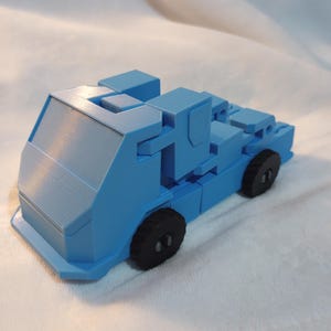 Pode incluir: Um caminhão de brinquedo azul claro com rodas pretas. O caminhão é feito de plástico e tem um design simples.