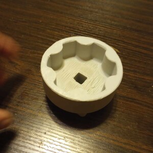 May include: White plastic socket wrench with a hexagonal opening. The socket is designed to fit a specific size bolt or nut.