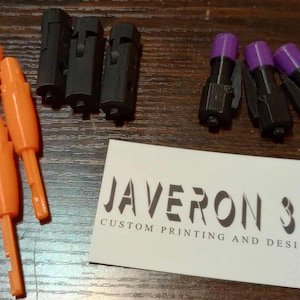 以下が含まれることがあります： 黒と白のビジネスカードに「JAVERON 3D CUSTOM PRINTING AND DESIGN」と書いてある、オレンジ色のプラスチック製のキーが3つあります。