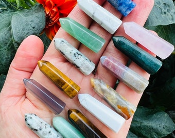 May include: A collection of 12 different crystal points, including amethyst, clear quartz, tiger's eye, and green aventurine. The points are arranged in a hand, with the tips pointing upwards.