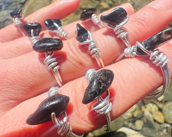 May include: A set of six silver wire wrapped rings with black gemstone accents. The rings are displayed on a hand.