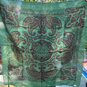 May include: A green paisley patterned silk scarf with a fringed edge.
