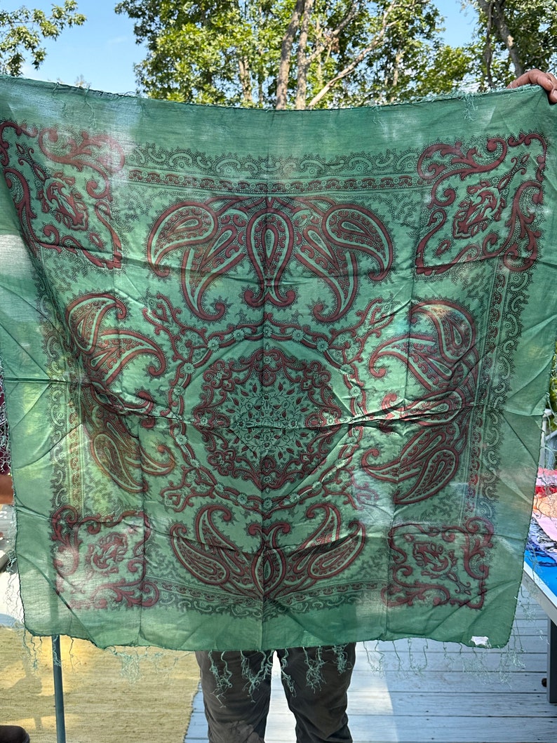 May include: A green paisley patterned silk scarf with a fringed edge.