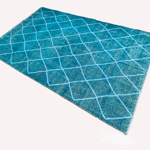 May include: A teal blue rug with a white diamond pattern. The rug is made of a soft, textured material and has a distressed look.
