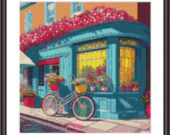 May include: A blue building with a flower shop storefront and a bicycle parked in front. The building is covered in red flowers and has a large window with yellow light shining through.
