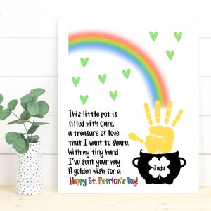 May include: A white card with a rainbow, green shamrocks, and a yellow handprint inside a black pot with the text "This little pot is filled with care, a treasure of love that I want to share. With my tiny hand I've sent your way A golden wish for a Happy St. Patrick's Day!" and the name "Jada" written inside the pot.