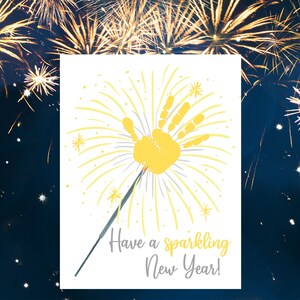 May include: A white card with a yellow handprint in the center, surrounded by yellow lines radiating outward, resembling fireworks. The text "Have a sparkling New Year!" is written below the handprint.