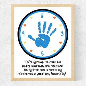 May include: A framed print with a blue handprint in the center of a clock face. The text reads "You're my round-the-clock fun guiding me each day from rise to sun. Now my little hand is here to say it's time to wish you a Happy Father's Day!"