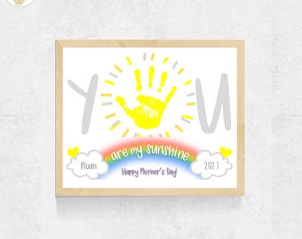 May include: A framed print featuring a yellow handprint as the center of a sun, with the text "YOU are my sunshine" and "Happy Mother's Day!" below. Two white clouds contain the name "Noah" and the year "2027" with small yellow hearts.