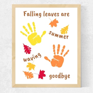 Puede incluir: Una impresión enmarcada con el texto "Falling leaves are summer waving goodbye" y dos huellas de manos, una amarilla y otra naranja, rodeadas de hojas rojas, naranjas y amarillas.
