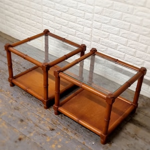 May include: Two wooden end tables with glass tops. The tables are made of light brown wood and have a simple, rectangular design. The glass tops are clear and add a modern touch to the tables.