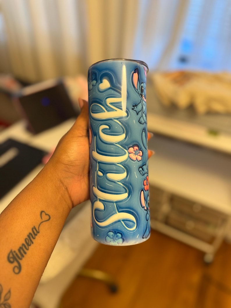 Puede incluir: Un vaso de acero inoxidable azul y blanco con un personaje de dibujos animados y la palabra "Stitch" en letras blancas.