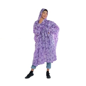 May include: A purple hooded raincoat with a geometric pattern. The raincoat has a button closure and long sleeves.