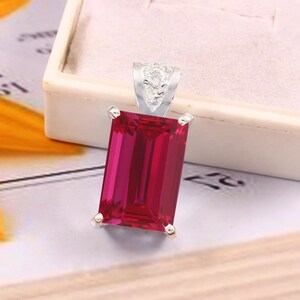 Puede incluir: Un colgante de plata con una gran piedra preciosa rectangular roja. La piedra preciosa está engastada en un engaste de plata y tiene un corte facetado.
