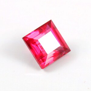 Könnte beinhalten: Ein quadratischer Edelstein in leuchtendem Pink mit facettiertem Schliff.