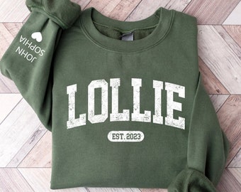 May include: A green sweatshirt with the text "Lollie Est. 2023" in white. The sleeve has the text "John Sophia" in white with a heart symbol.