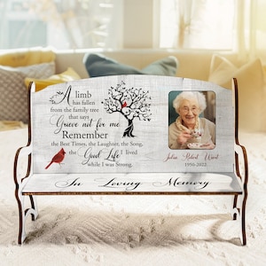May include: A white wooden bench with a photo frame and a quote about remembering a loved one. The quote reads "A limb has fallen from the family tree that says Grieve not for me Remember the Best Times, the Laughter, the Song, the Good Life I lived while I was Strong." The photo frame has a black and white photo of an older woman with a white background. The bench has the words "In Loving Memory" on the front.